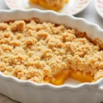 Golden Peach Crumble With A Crunchy Oat Topping Served In A White Baking Dish